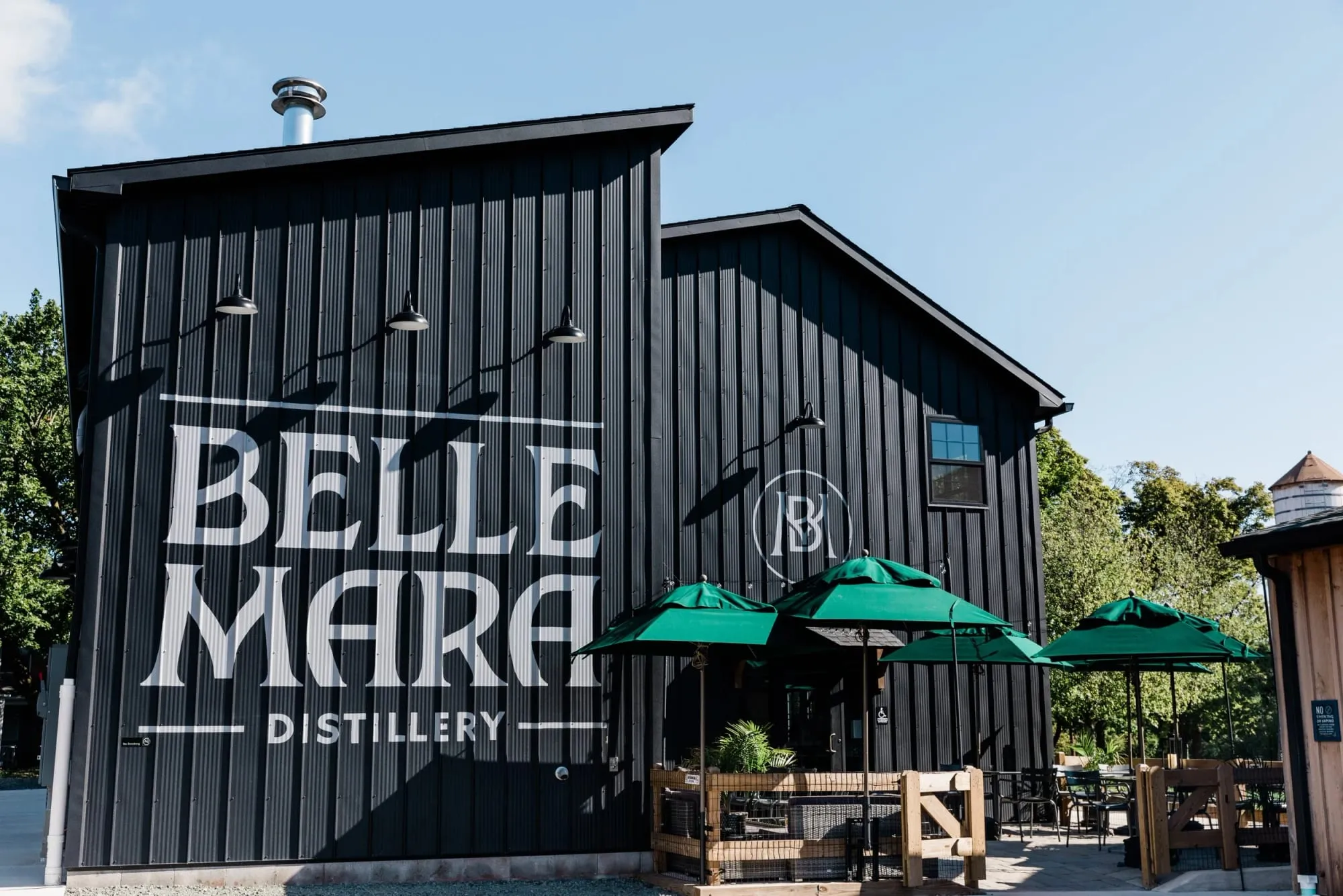 Bellemara Distillery’s black barn and green-umbrella patio on Carriage Farm