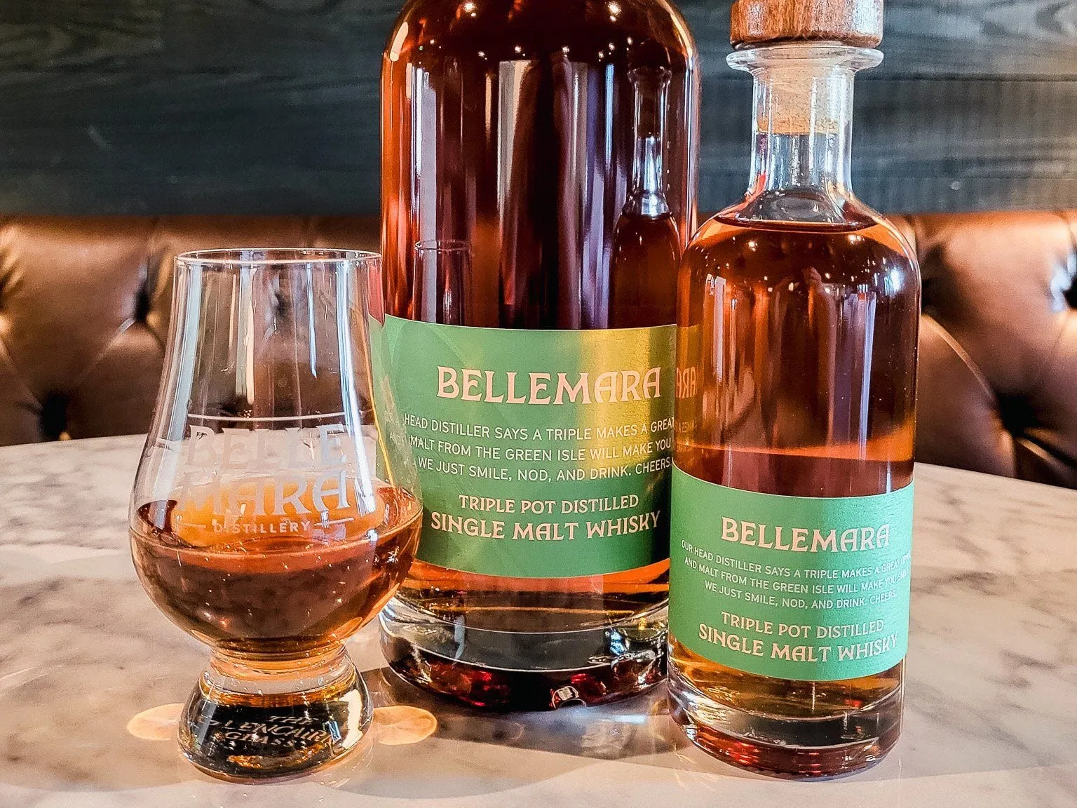 A pour of Bellemara triple pot distilled single malt whisky in a tasting glass beside two bottles