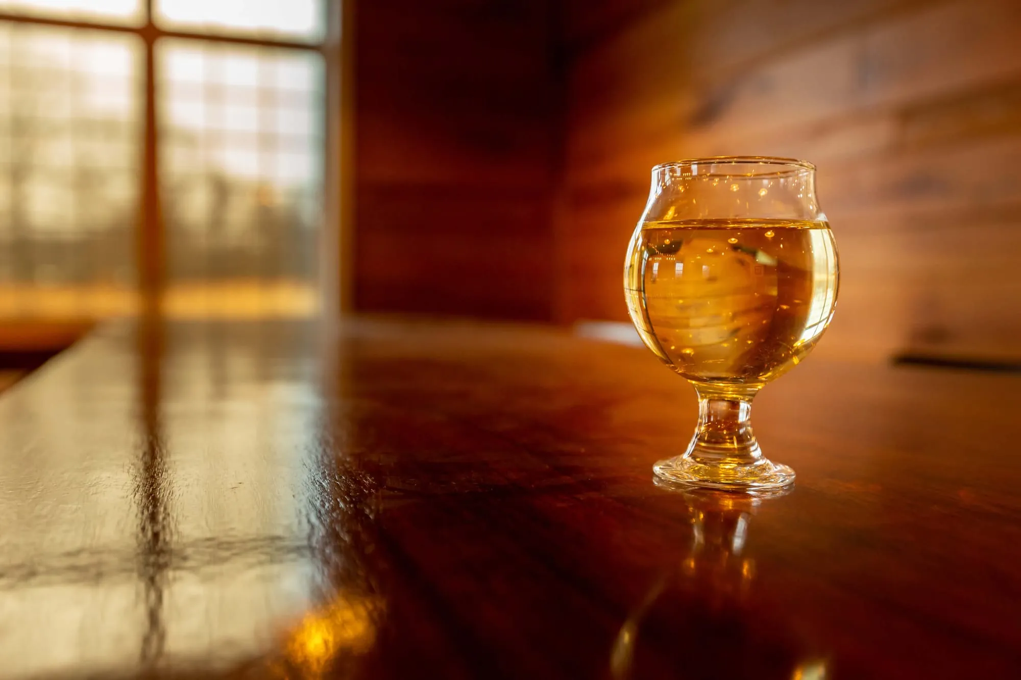 A glass of hard cider on the bar at Burnt Mills Cider