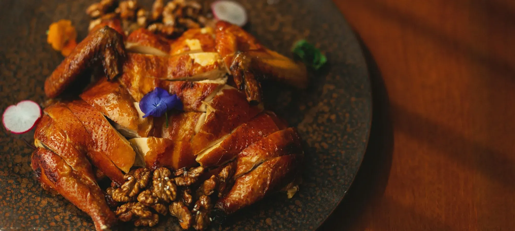 Carved roast duck with glossy skin on a dark plate
