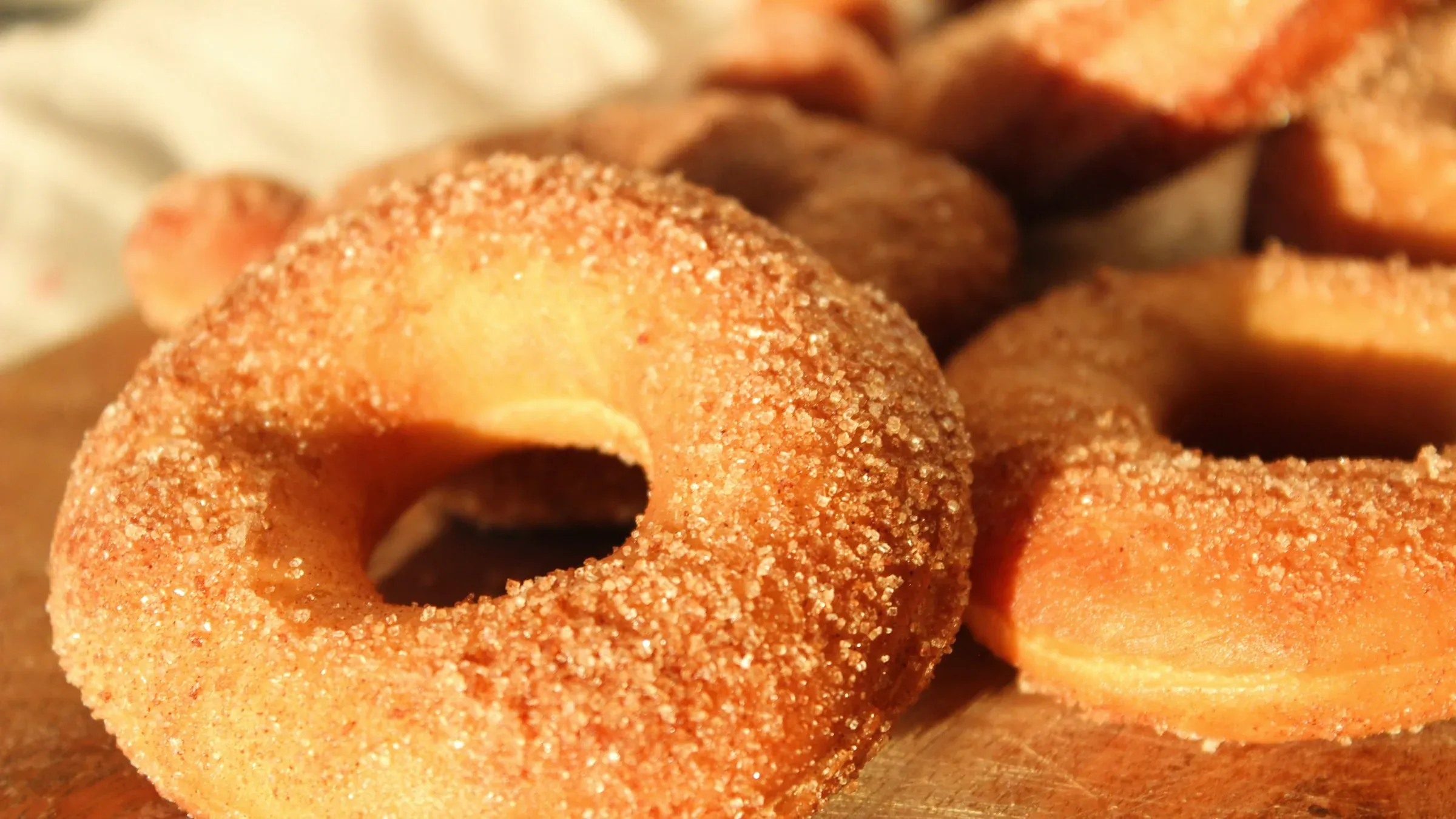 Sugar-coated apple cider doughnuts on a wooden board