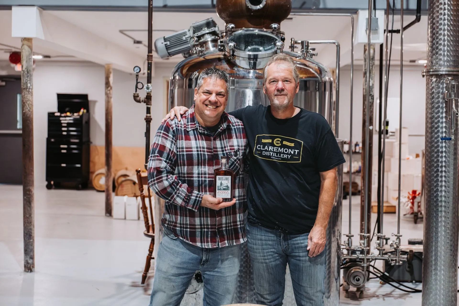 The owners of Claremont Distillery with a barrel among the stills