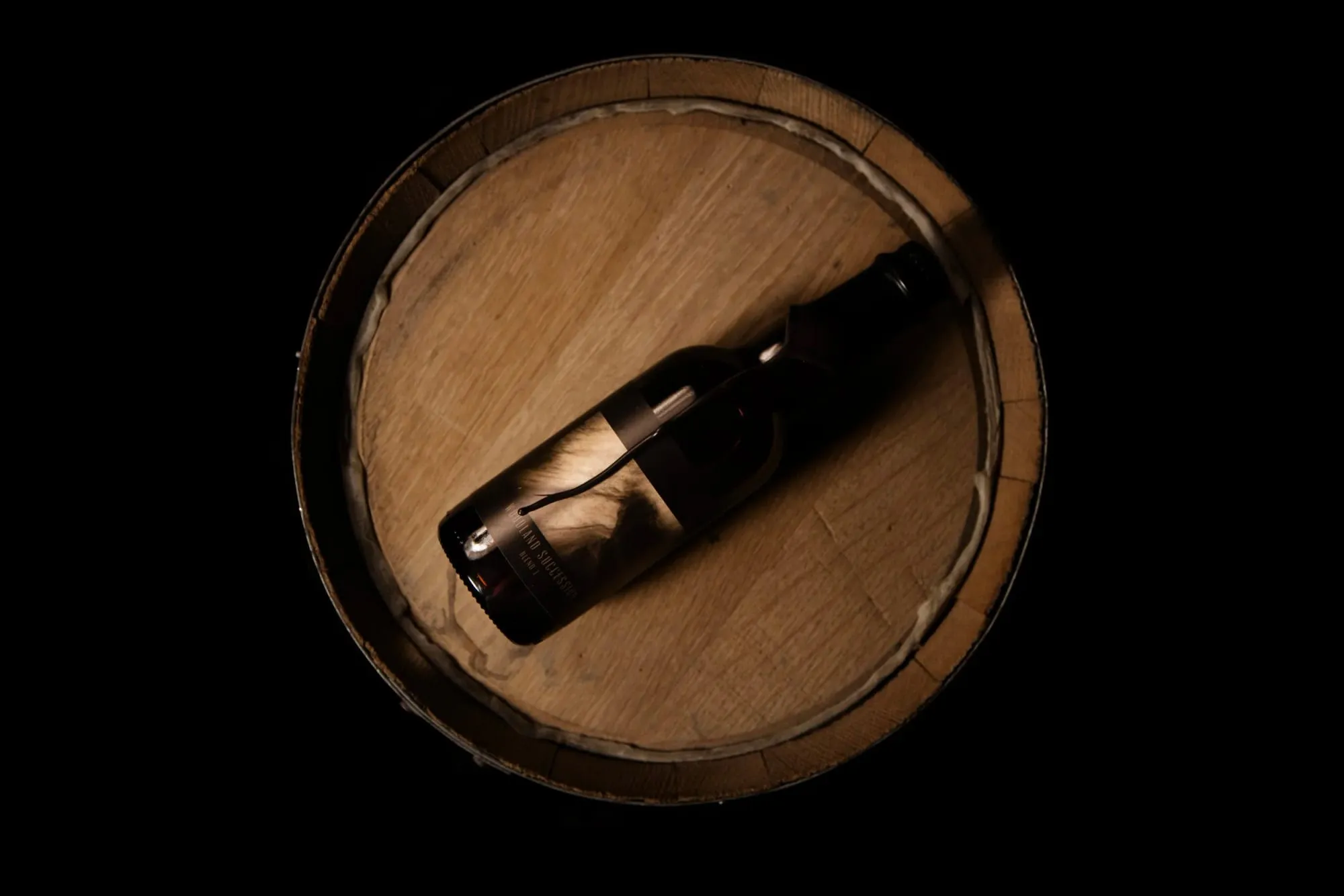 A bottle of Esker Hart ale resting on a barrel head