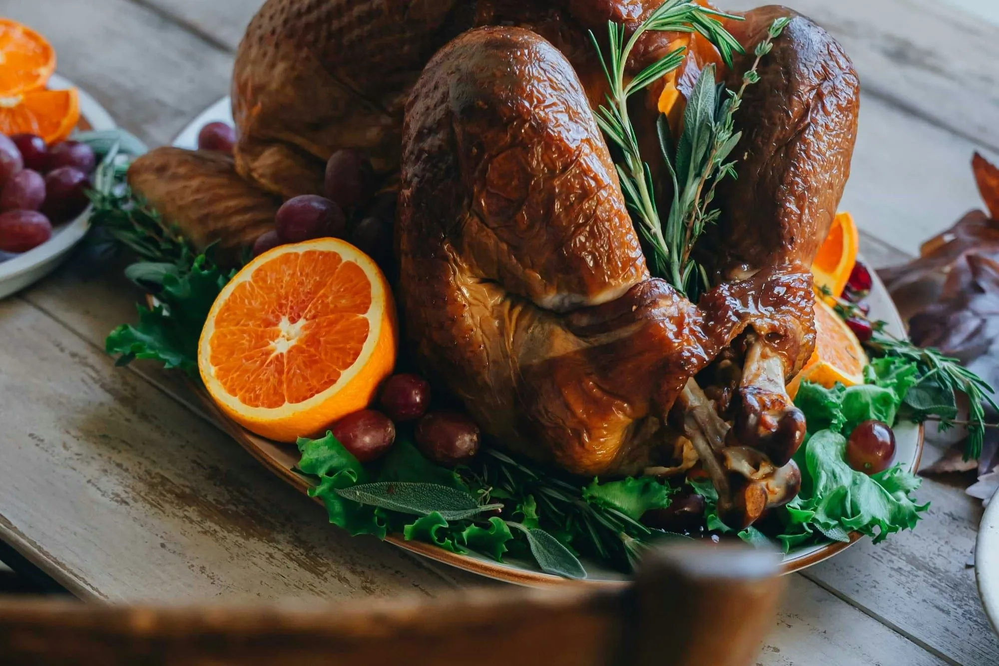 A golden roasted turkey garnished with oranges and rosemary on a wooden table (stock photo)