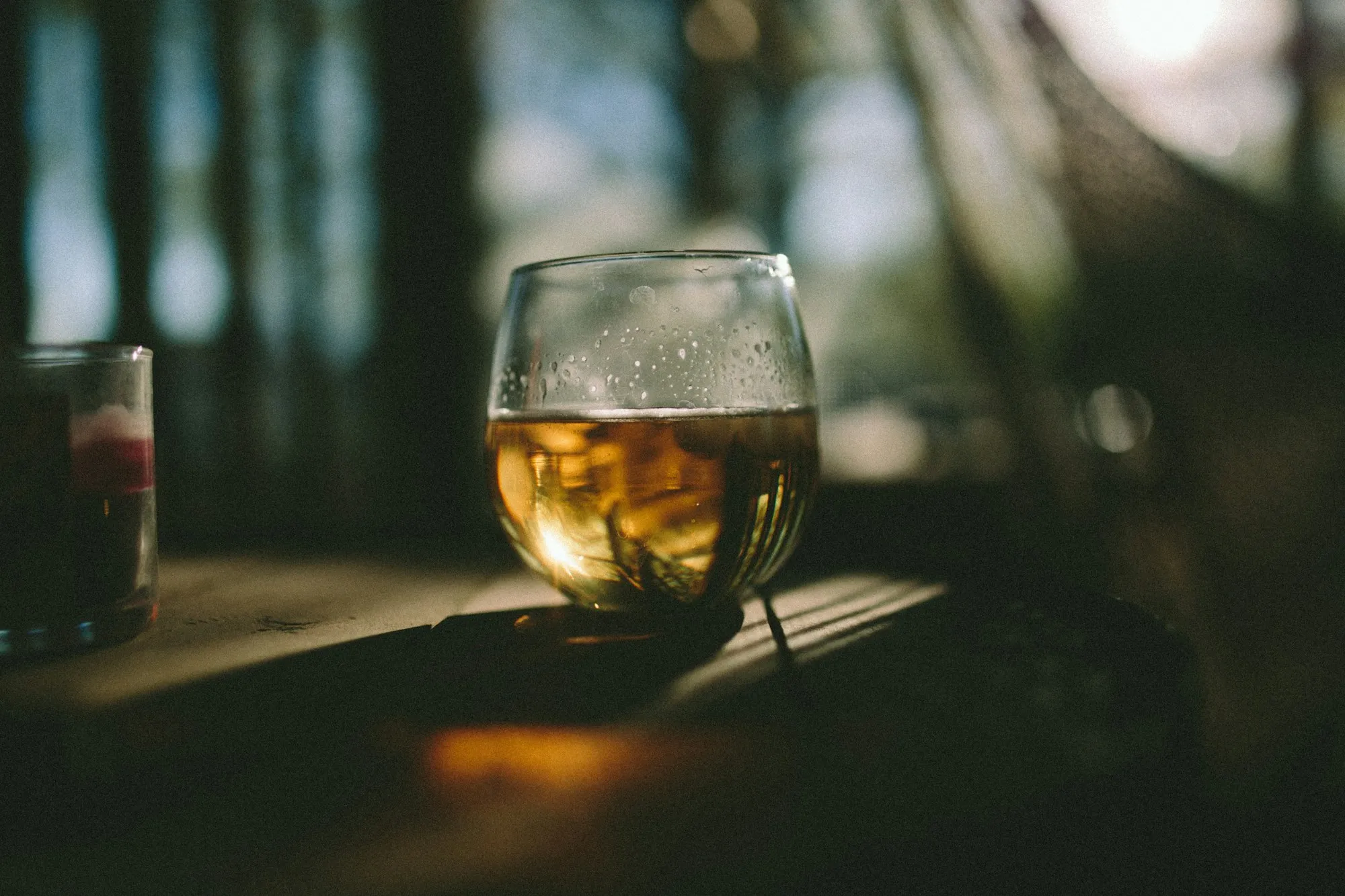 A glass of golden wine on a wooden table in warm evening light (stock photo)