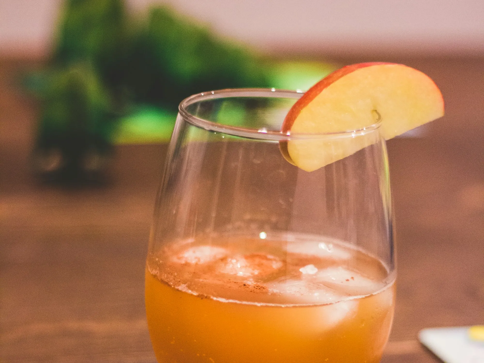 A glass of sparkling cider over ice with an apple slice on the rim (stock photo)