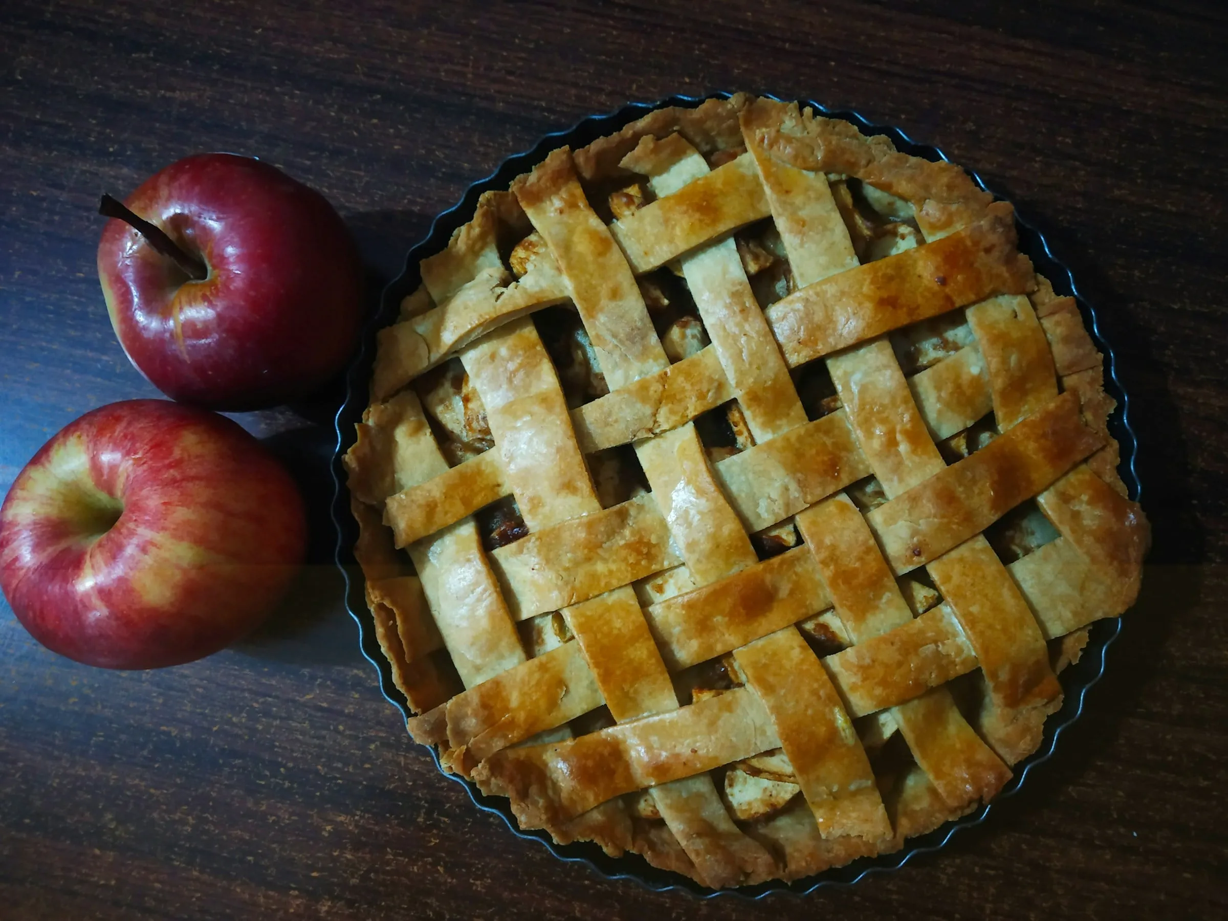 A lattice-top apple pie beside red apples (stock photo)