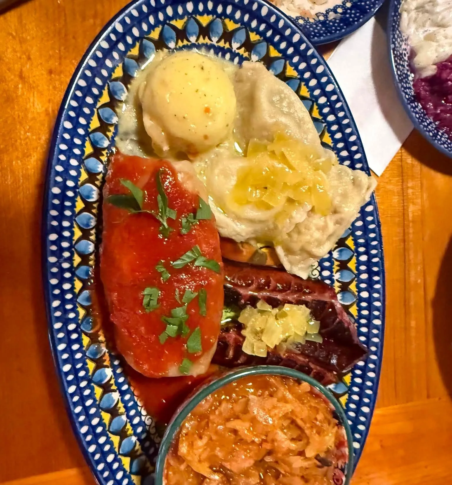 A Polish platter of stuffed cabbage, pierogi, kielbasa and bigos on a hand-painted Polish pottery plate
