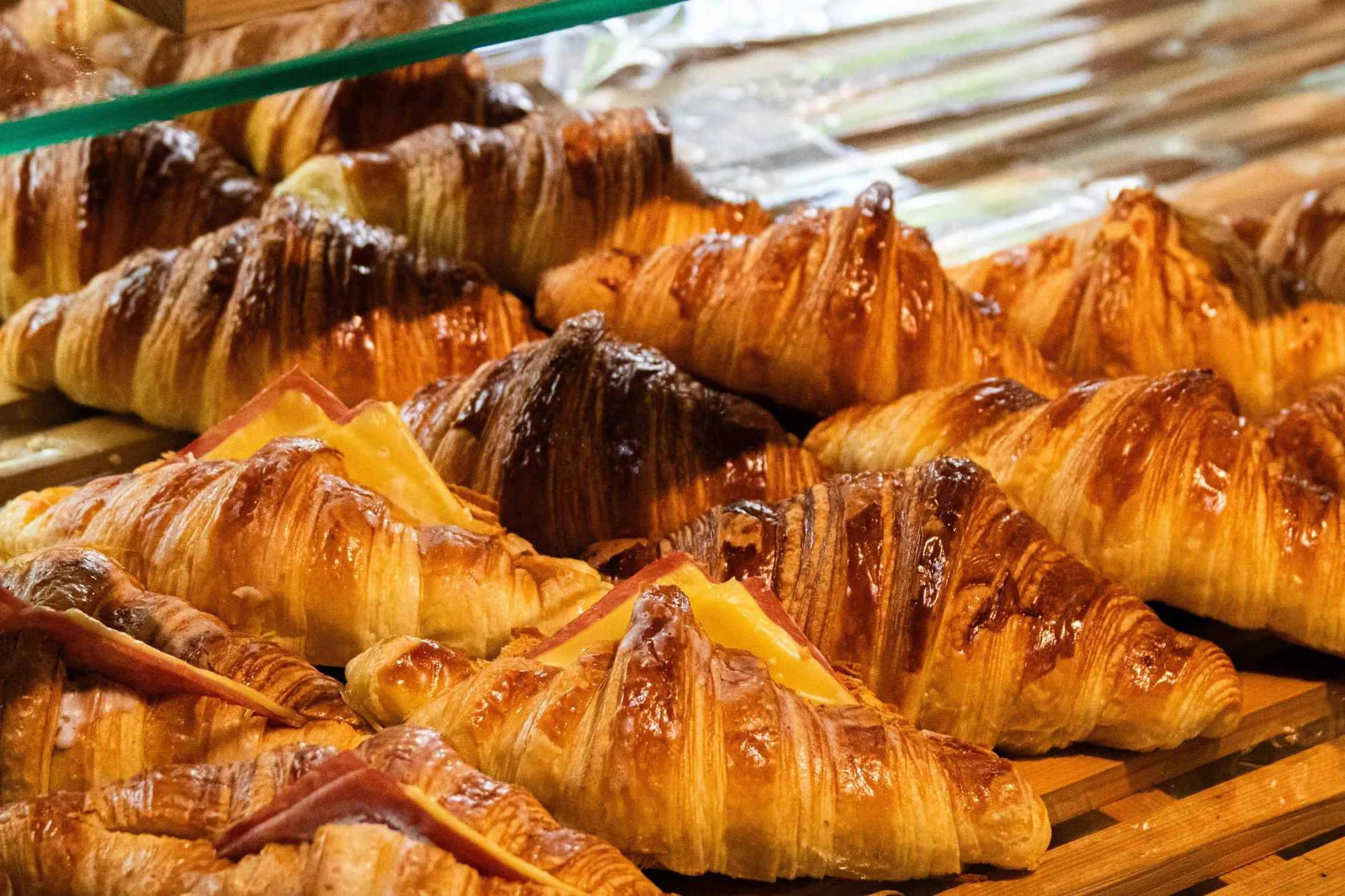 Rows of glossy, flaky butter croissants on a bakery rack (stock photo)