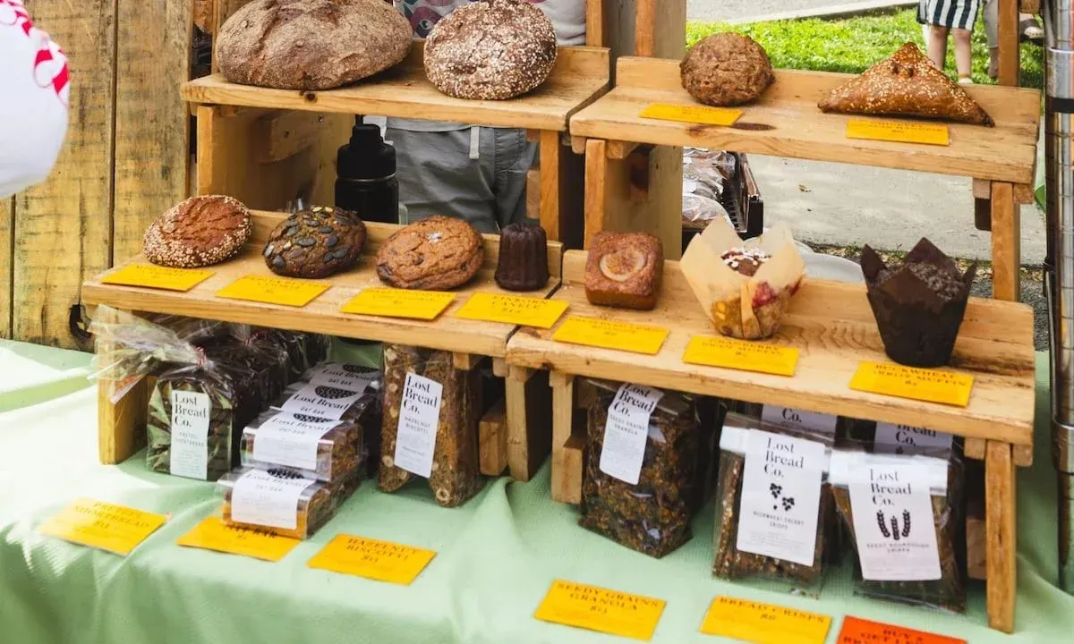 Crusty loaves, cookies, canelés and muffins on wooden shelves at the Lost Bread Co. stall