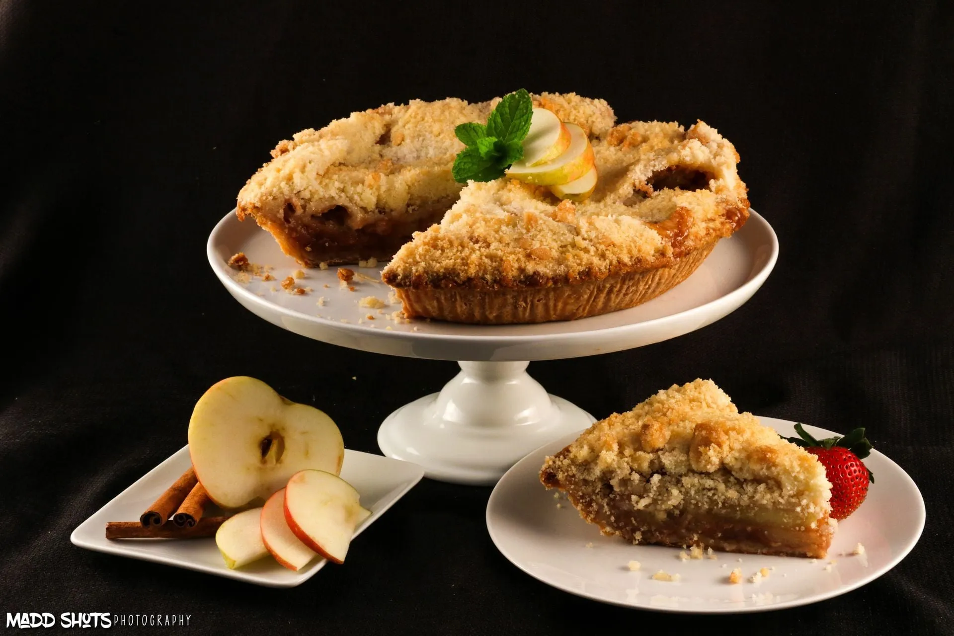 Maddalena’s apple crumb pie with a slice cut, beside fresh apples