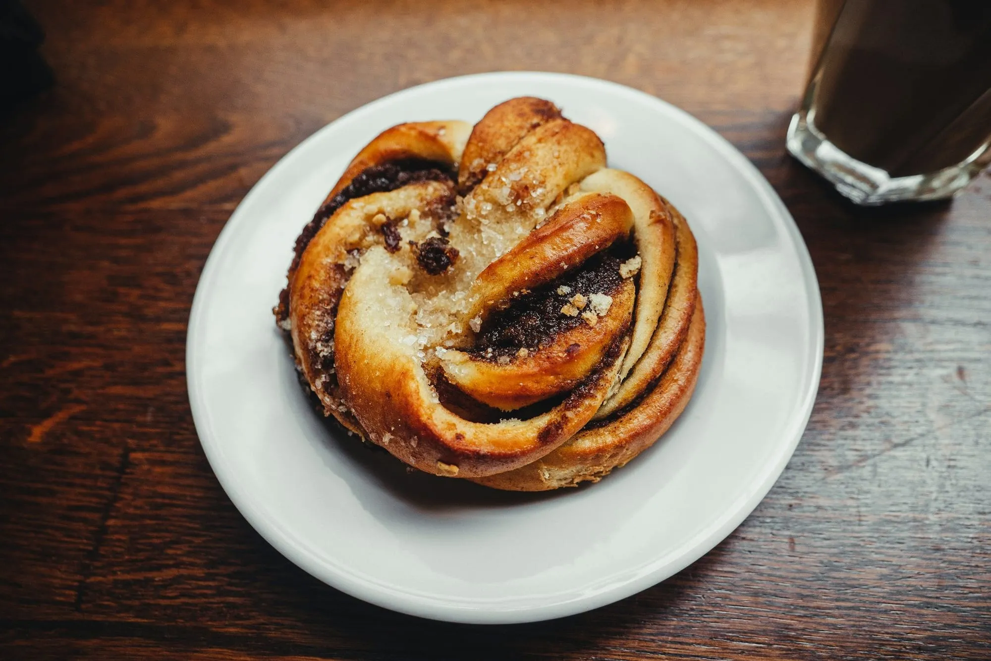 A twisted chocolate swirl bun on a white plate (stock photo)