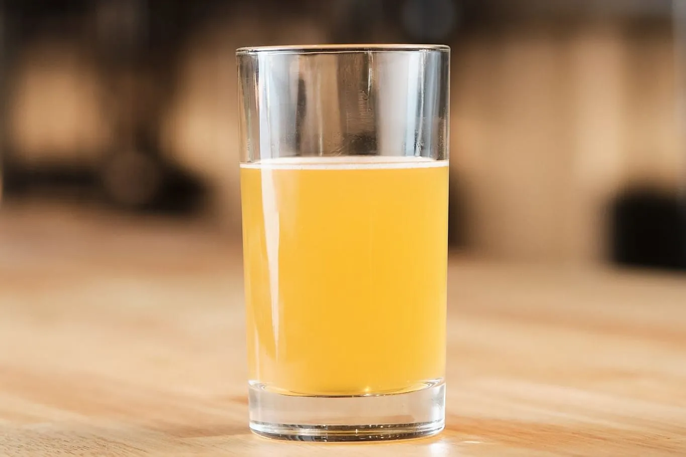 A glass of golden honey wine on a wooden bar