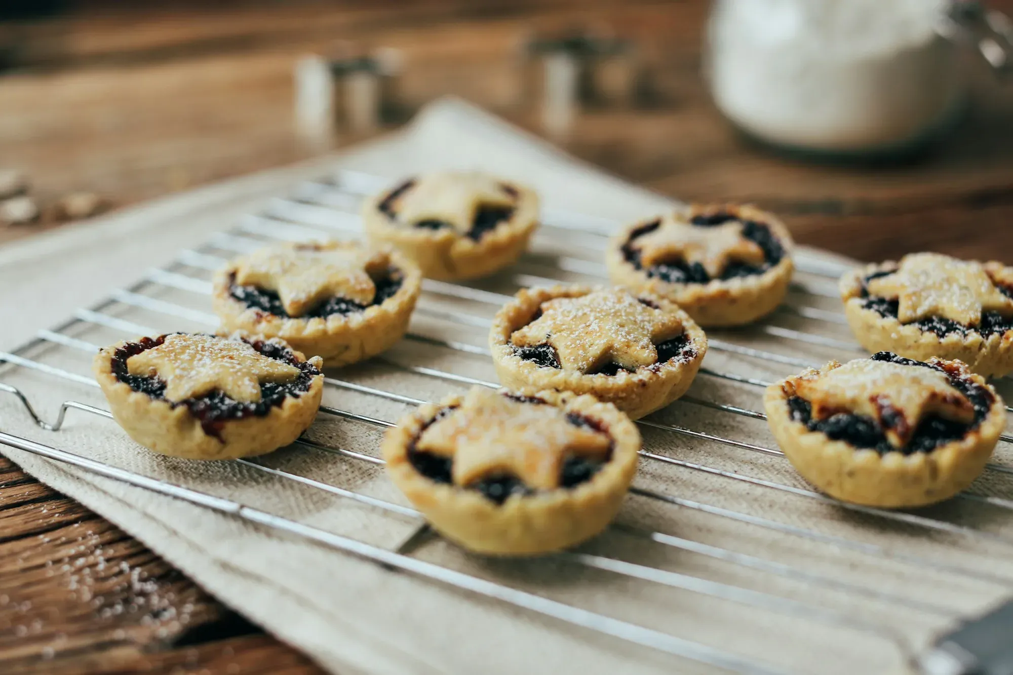 Freshly baked mince pies with star-shaped lids on a cooling rack