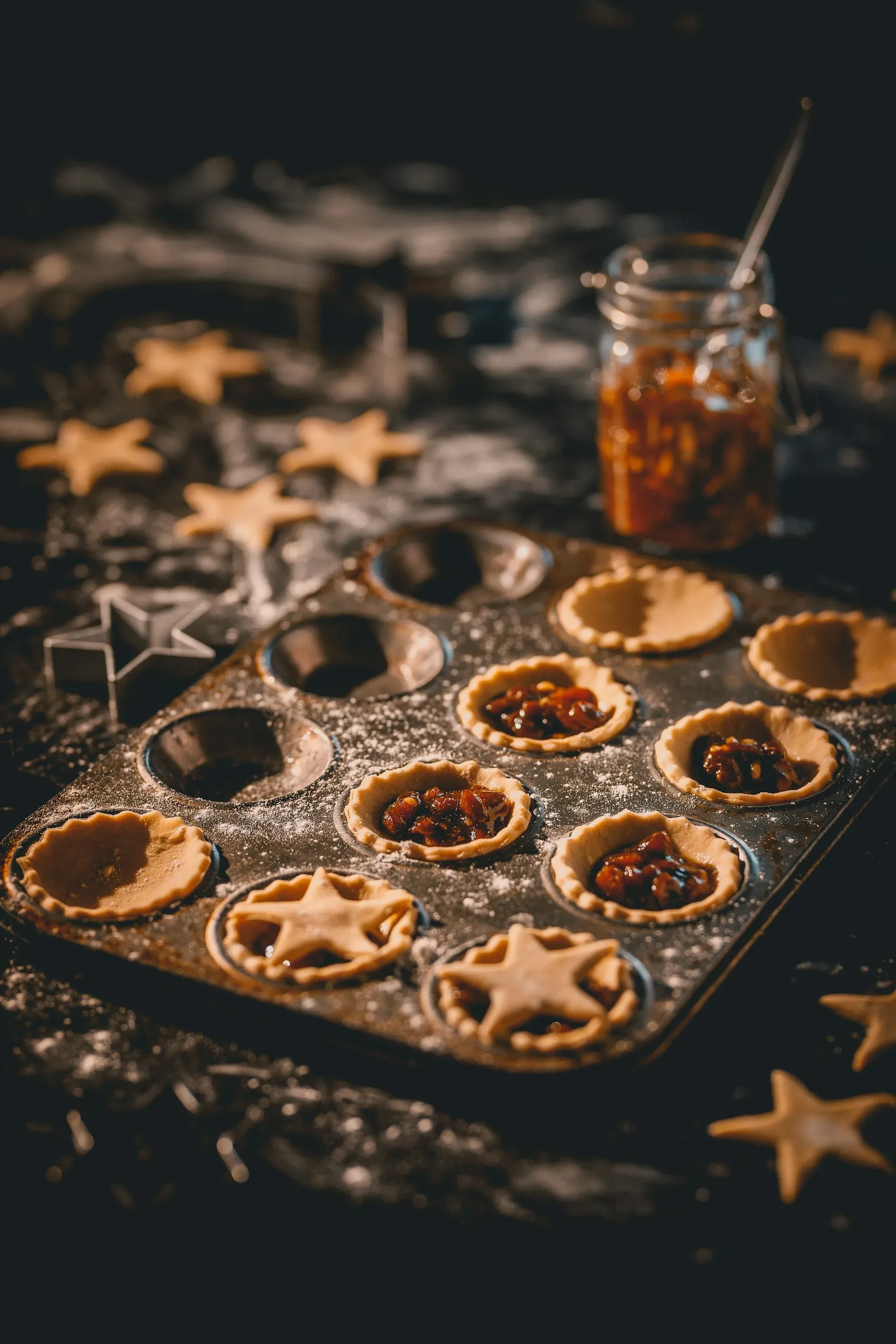 Small mince pies with star lids in a dark baking tin