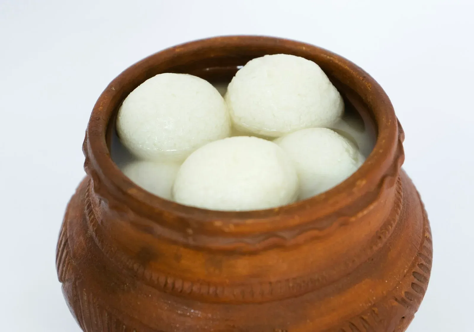 Soft white rasgulla in syrup in a clay pot