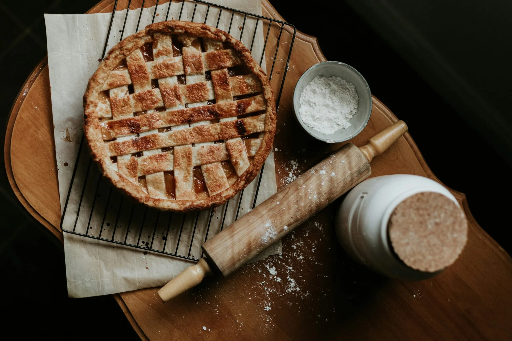 A lattice-top fruit pie cooling on a rack beside a rolling pin (stock photo)