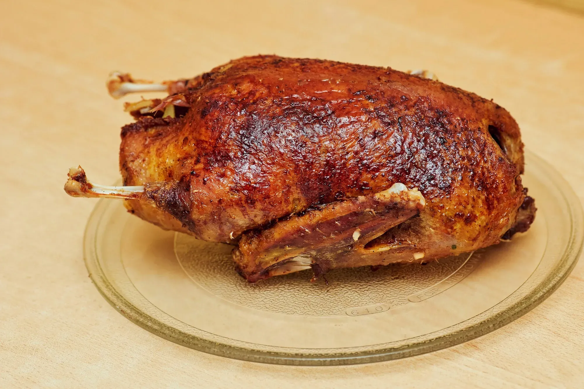A whole roast bird with crisp mahogany skin on a round platter