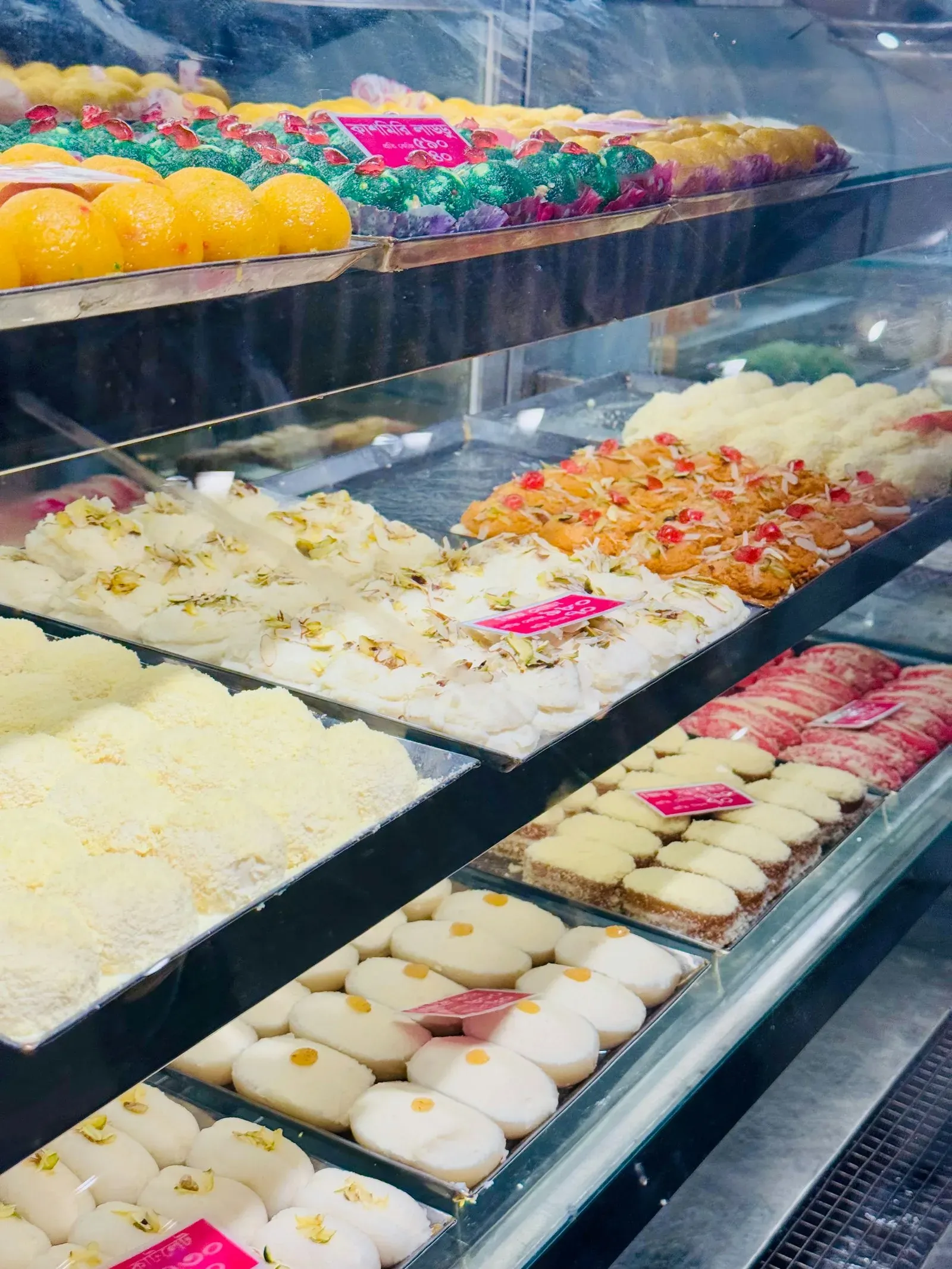 Glass cases of colorful Indian sweets in a sweet shop