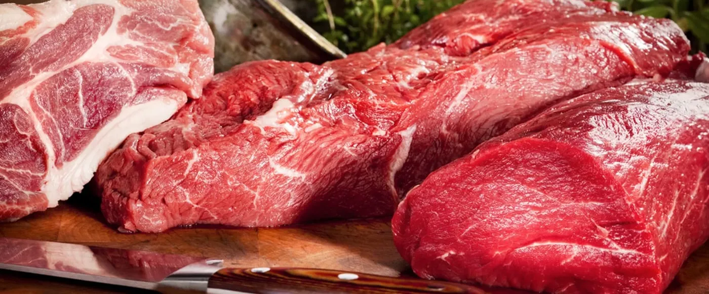 Raw beef roasts and a pork shoulder steak on a wooden butcher board