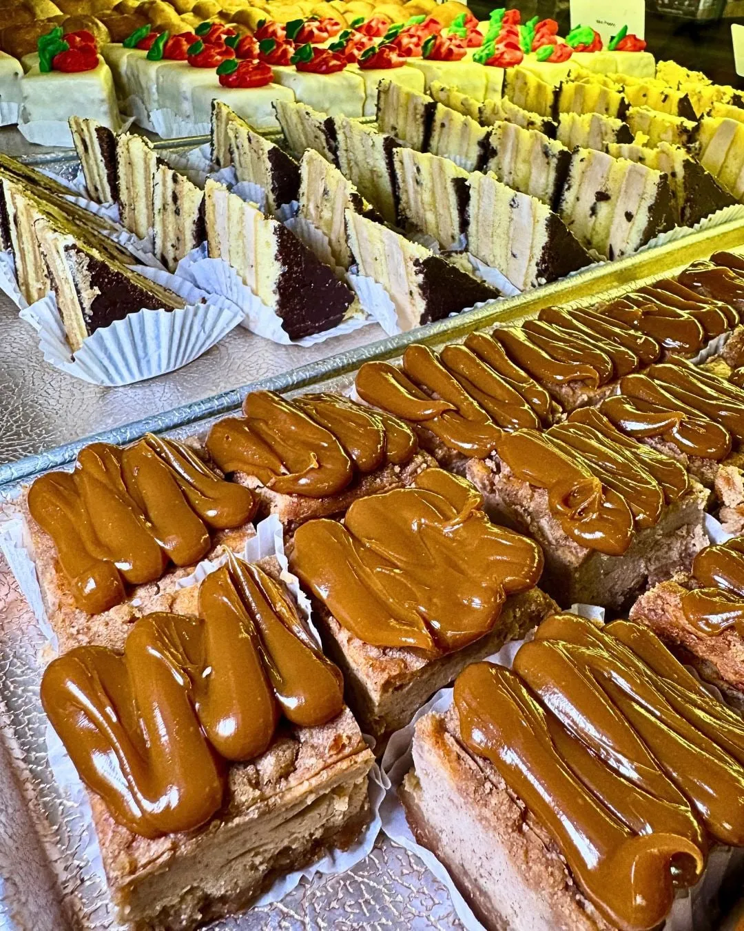 Caramel-topped pastries and rainbow cookie slices in the case at Sorrento Bakery