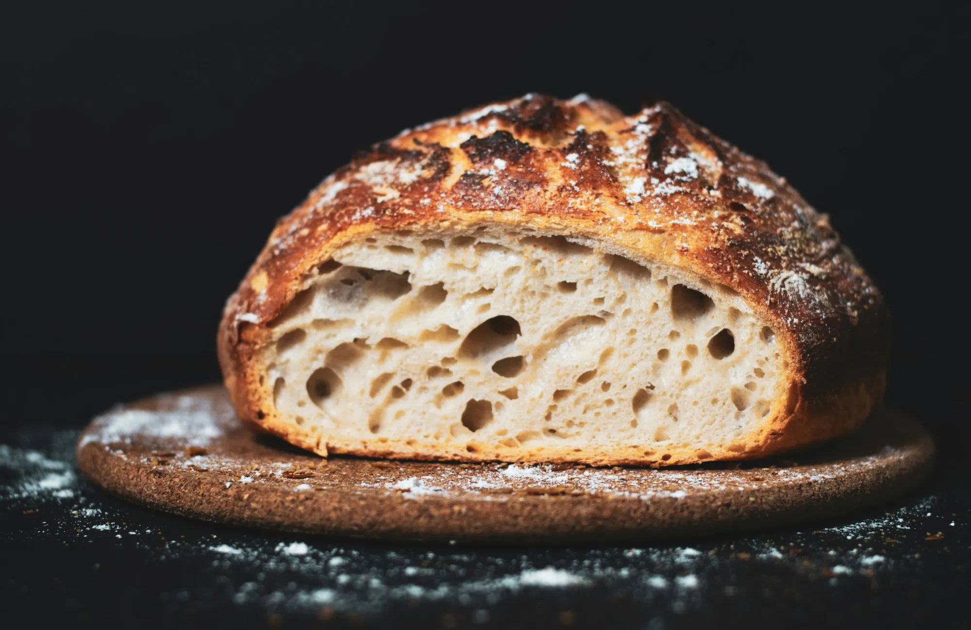 A dark-crusted sourdough loaf cut open to show its open crumb (stock photo)