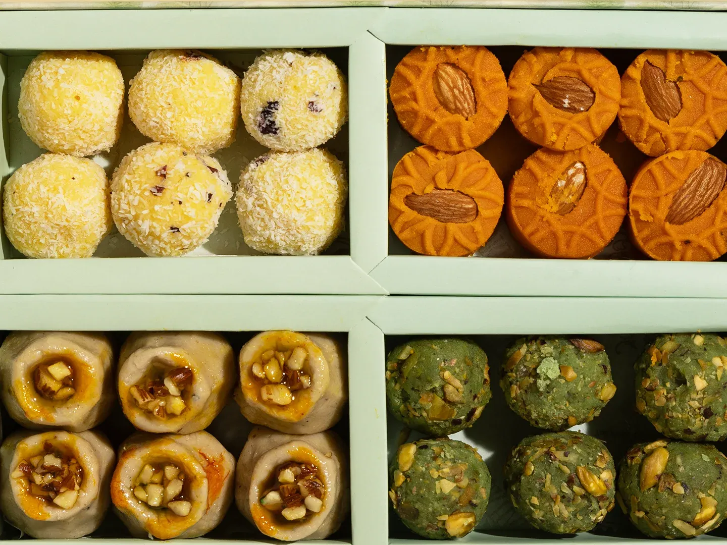 A box of mithai from Sukhadia’s: coconut ladoo, almond-topped peda, nut-filled rolls and pistachio sweets
