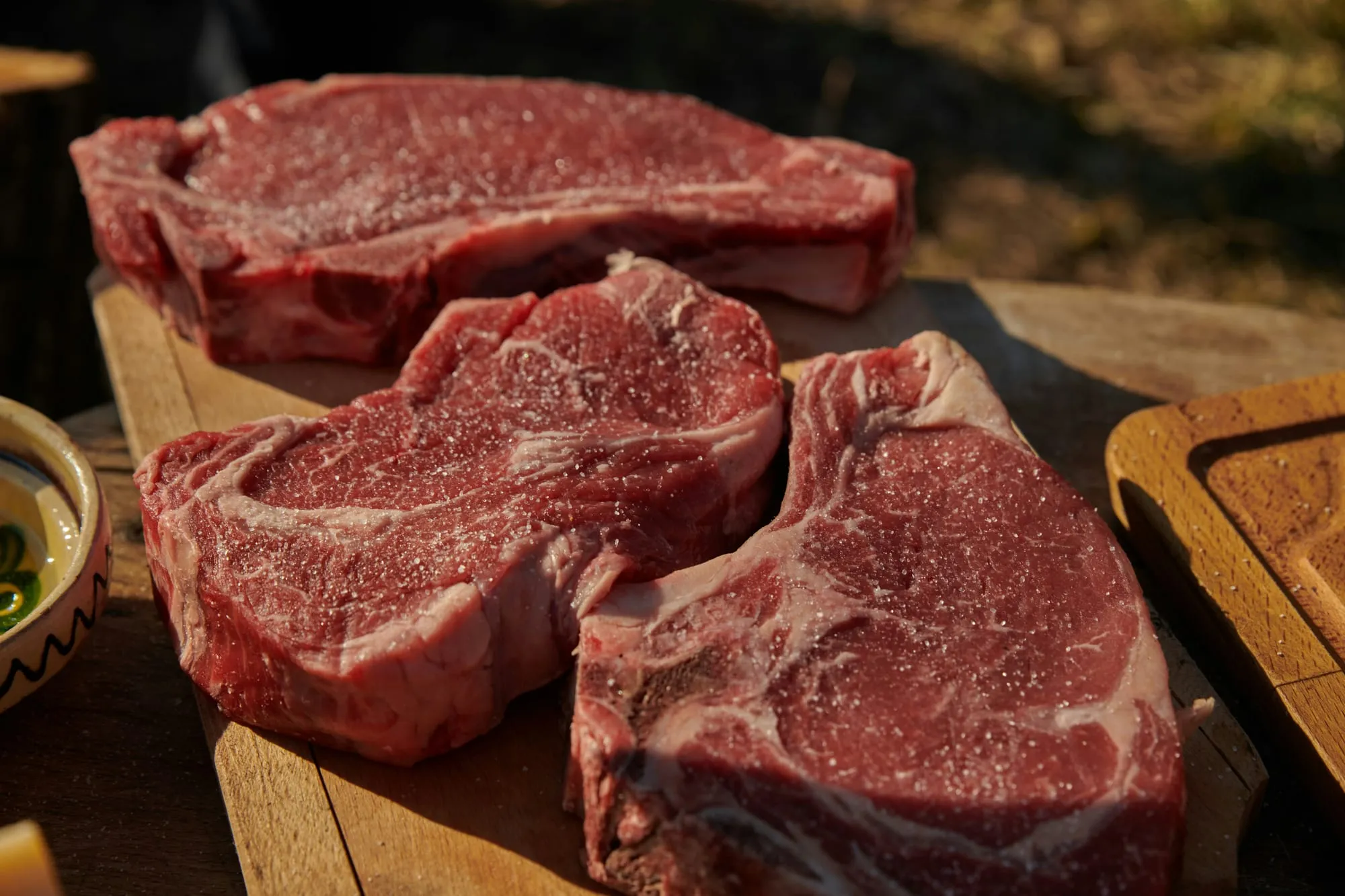 Thick raw bone-in steaks on a wooden cutting board (stock photo)