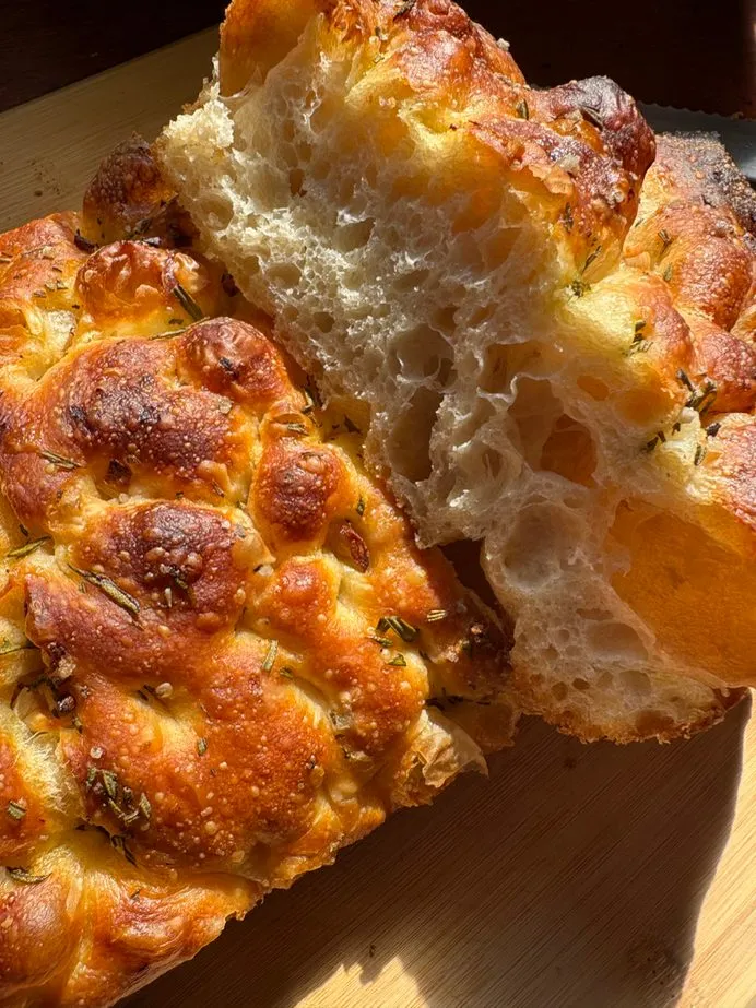 Golden rosemary sourdough focaccia torn open to show its airy crumb
