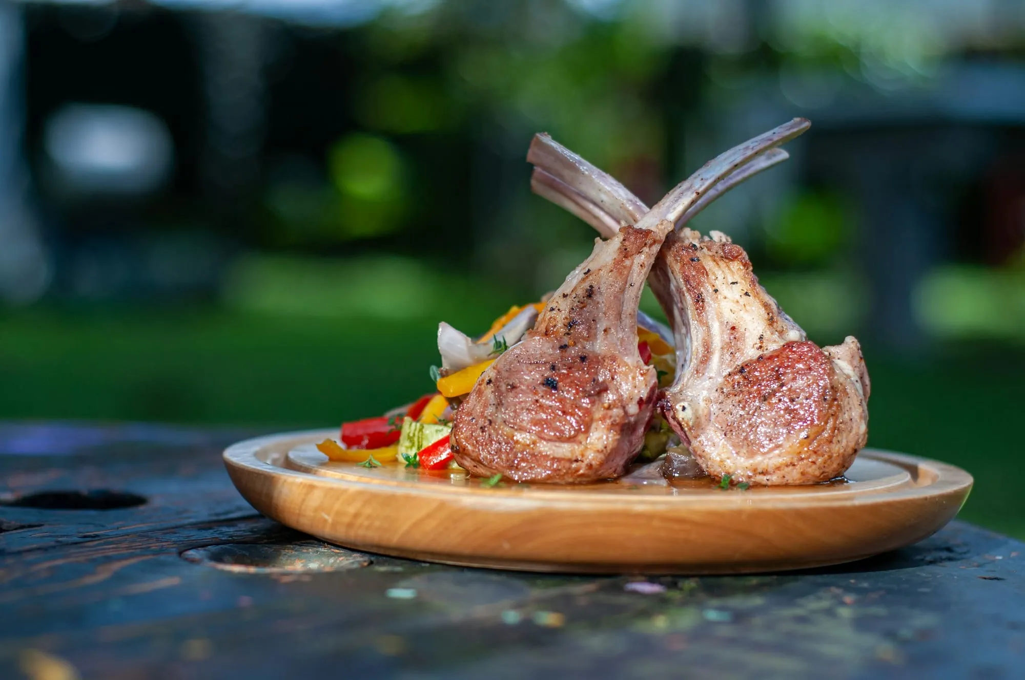 Grilled lamb rib chops on a wooden plate with roasted vegetables (stock photo)